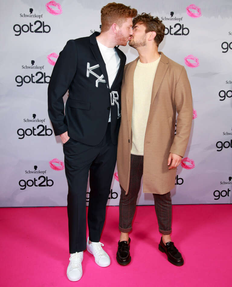 Deux hommes s’embrassent sur le tapis rose de l’événement got2b.