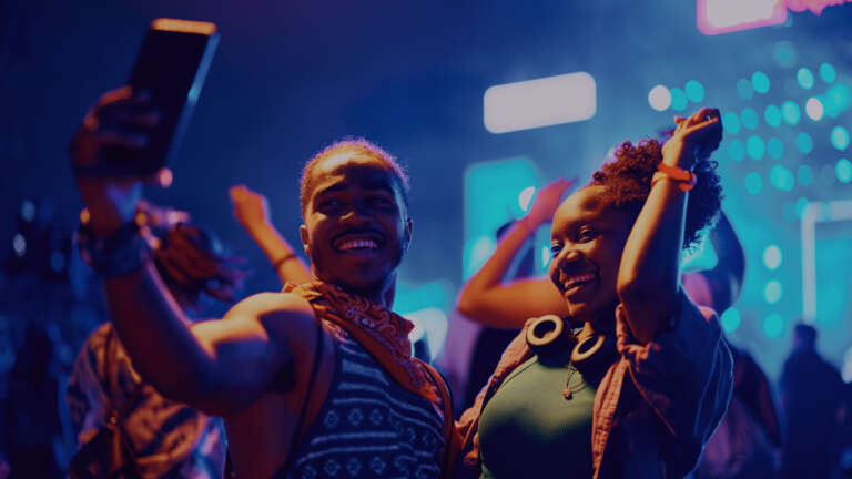 Deux amis souriants prenant un selfie en pleine soirée, incarnant la convivialité et le plaisir d’être ensemble