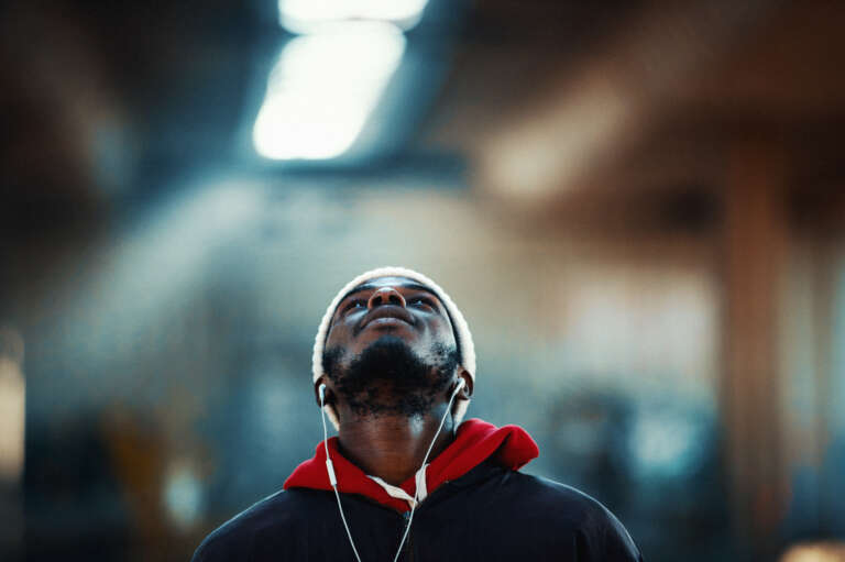 Young man looking up while listening to music in an urban setting